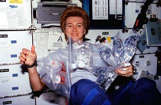 STS-84 Mission Specialists Elena Kondakova holds a bundle of biomedical, environmental and water samples in the middeck. 